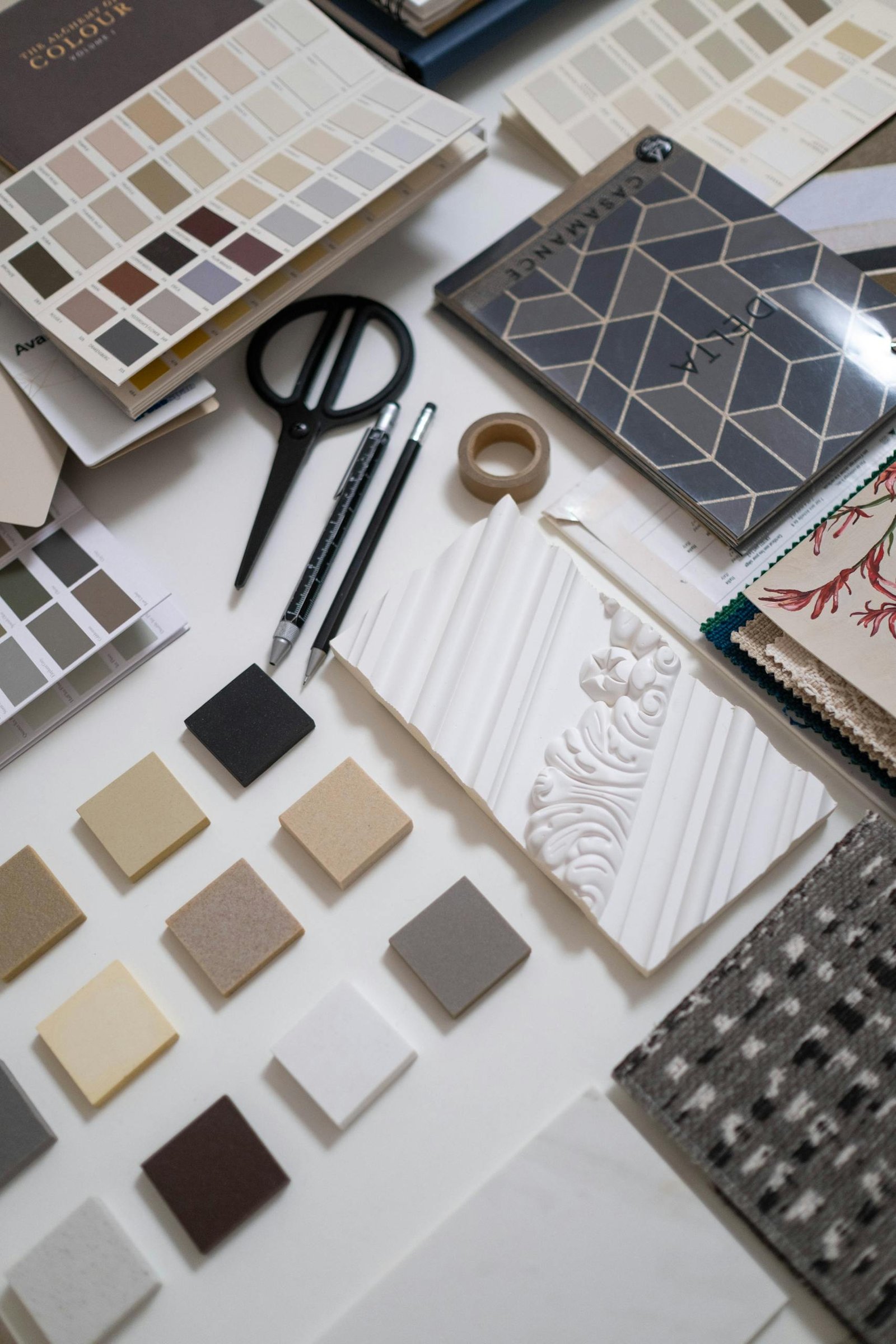 A flat lay of a designer's workspace featuring color swatches and material samples for interior design.